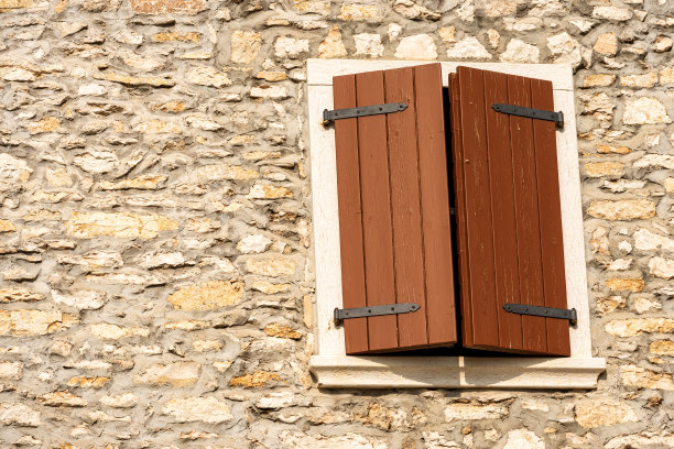 石头墙上装有紧闭的木百叶窗的窗户图片下载