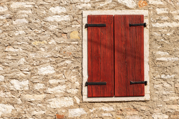 石头墙上装有紧闭的木百叶窗的窗户图片下载