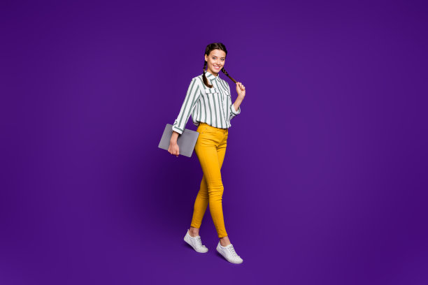 全身照片美丽的商务女士拿着笔记本双手行走学生讲课课穿条纹衬衫黄裤子孤立的紫色背景图片下载