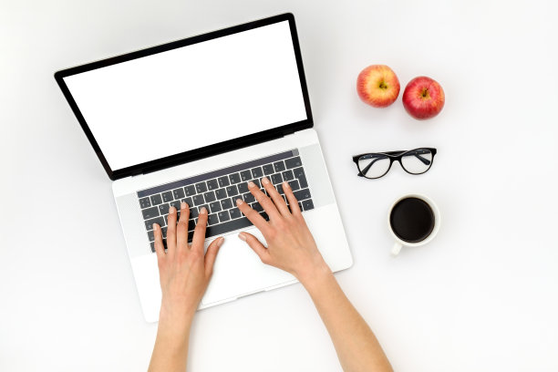 俯视图美丽的女人的手使用笔记本电脑放在白色的桌面上。平躺图片下载