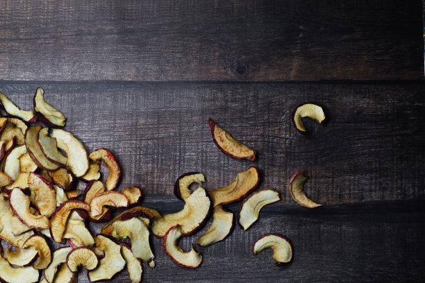干苹果片放在棕色的木桌上。有机天然食品。前视图。平的。图片下载