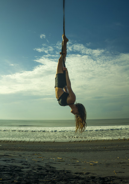 空中瑜伽海滩锻炼-年轻迷人和运动女子练习空中瑜伽练习训练杂技身体姿势在蓝天上在巴厘岛海上健康的生活方式概念图片下载