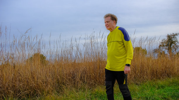 一个戴着智能手表的老人在高高的草丛中行走图片下载