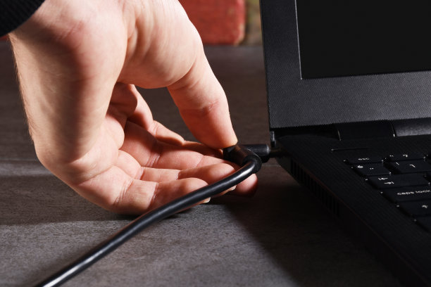 一只公手插着笔记本电脑的电池线图片下载