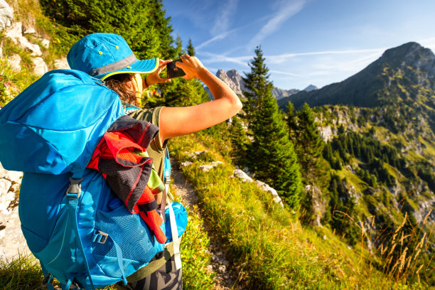 女游客站在山脊上用智能手机拍照图片下载