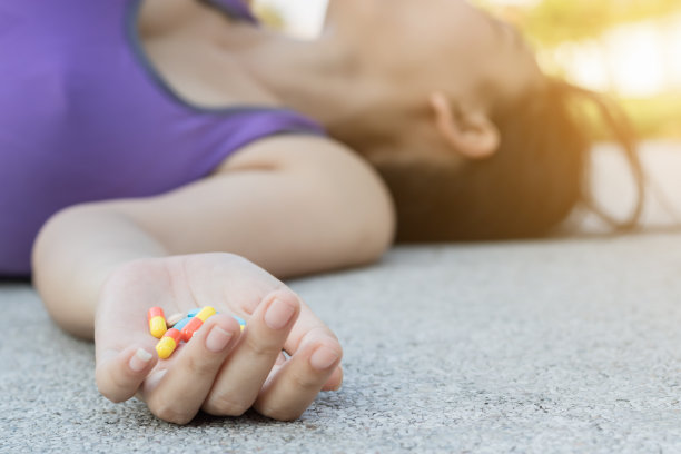 穿着运动服的年轻女子摔倒在人行道上失去知觉，试图吃手里的减肥药图片下载