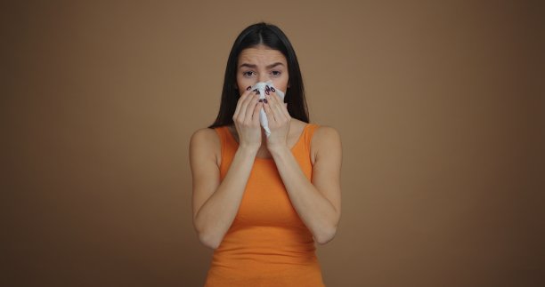 生病的黑发女人打喷嚏孤立的棕色背景图片下载