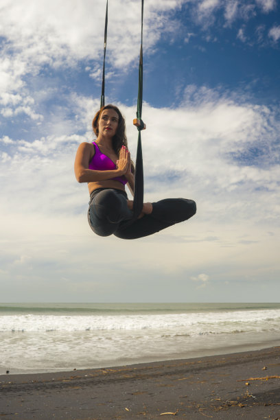 空中瑜伽海滩锻炼-年轻有吸引力和运动员女子练习空中瑜伽冥想练习在海上训练杂技身体姿势隔离在蓝天在平衡灵活性图片下载