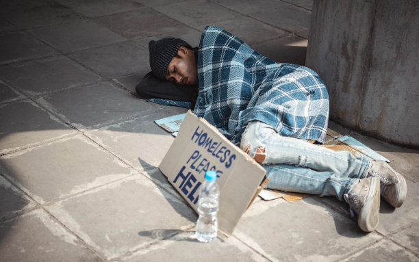 可怜的无家可归者或难民睡在城市街道上的木凳上图片下载