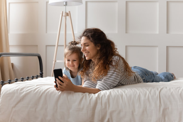 幸福的家庭在智能手机上看有趣的卡通。图片下载