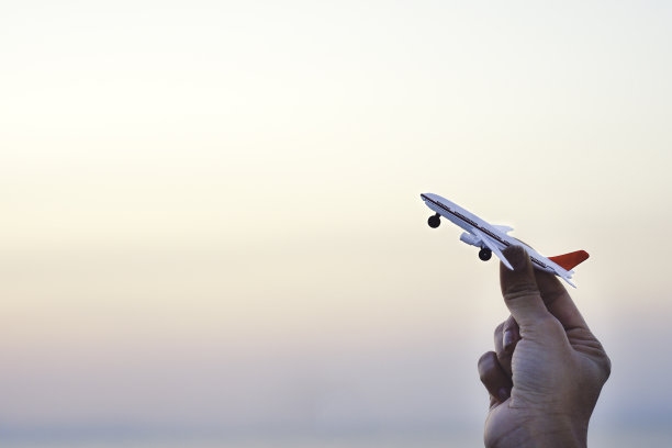 女人手握飞机模型在日落的天空和夏天的海背景梦想旅行度假。图片下载