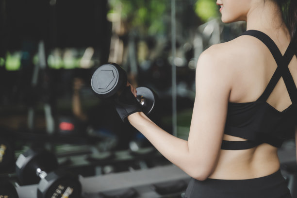 在健身房用哑铃锻炼的健美亚洲女性背影，健康生活方式概念图片下载