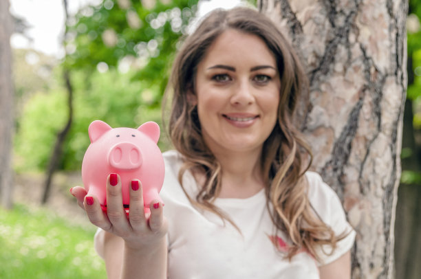 特写肖像快乐，微笑的商业女人，抱着储蓄罐，孤立的户外绿树背景。金融储蓄，银行概念。积极的情绪，面部表情图片下载