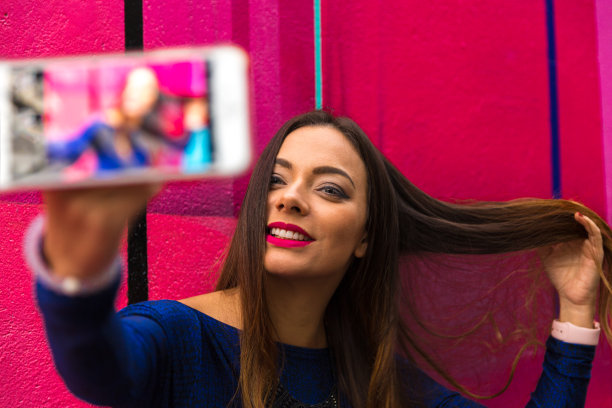 时尚漂亮无忧无虑的女人在彩色的抽象背景自拍照片图片下载