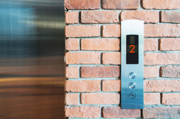 特写镜头的电梯按钮。以旧红砖墙为背景。景深浅。图片下载