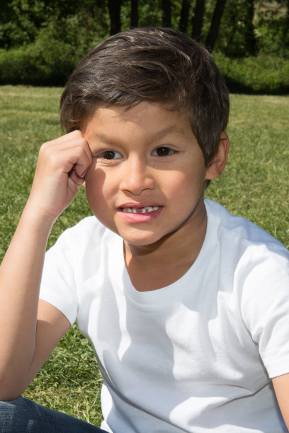 一个小男孩坐在绿色的草地上图片下载