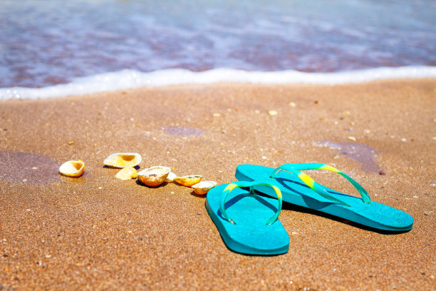 蓝色的拖鞋站在海边的沙子上图片下载