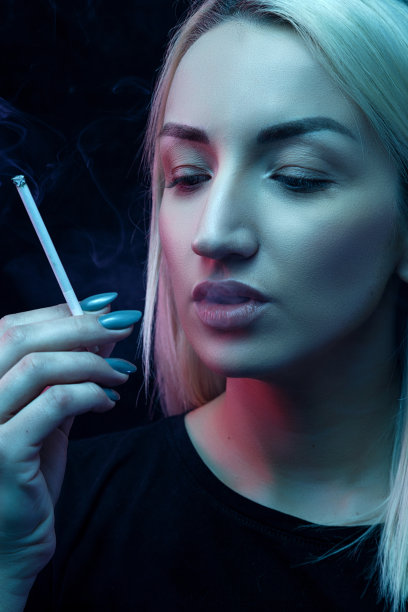 年轻的白种金发美女在抽烟。特写肖像在霓虹灯图片下载