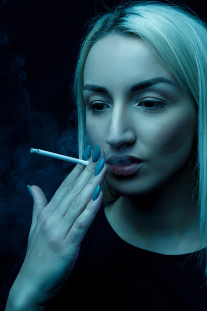 年轻的白种金发美女在抽烟。特写肖像在霓虹灯图片下载