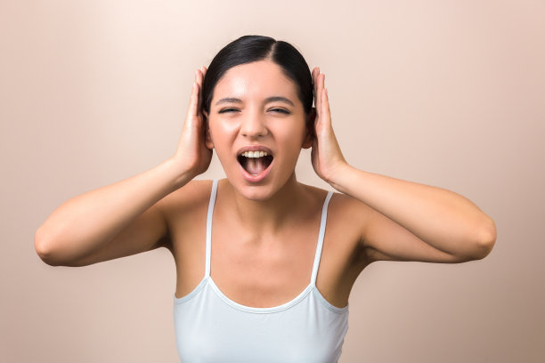 美丽的女人沮丧的噪音尖叫和捂住她的耳朵图片下载