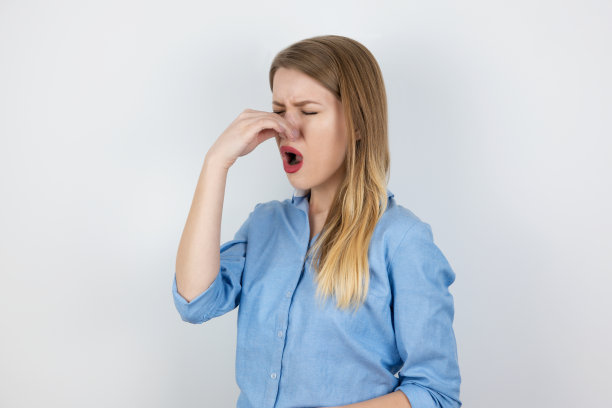 因异味捏住鼻子的年轻金发女性图片下载