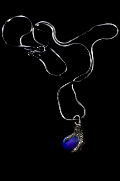 美丽的鸟爪子形状的银色吊坠，蓝色的石头球和链子孤立在黑色的背景图片下载