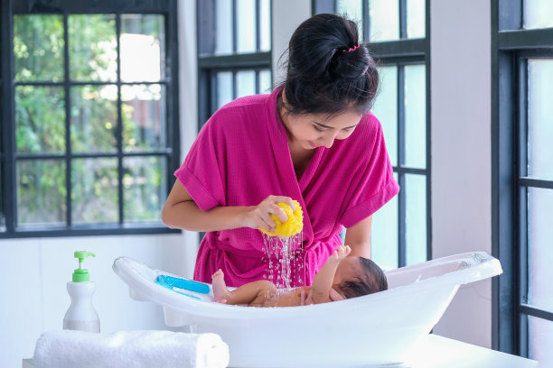 2个月大的婴儿躺在白布上，沐浴着清晨的阳光。图片下载