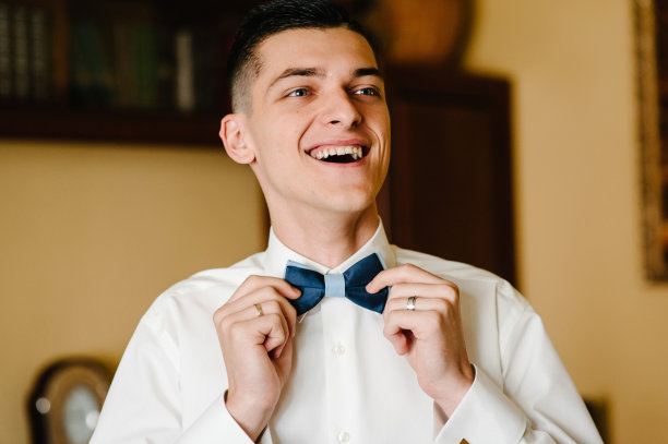时尚男士纠正衬衫上的领结。早上准备在家梳妆。图片下载