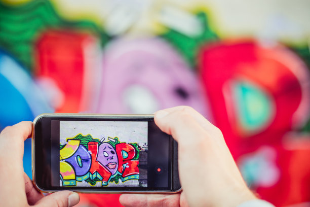 一个年轻人正在用他的智能手机拍摄涂鸦图片下载