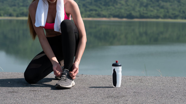 年轻的亚洲女子系鞋带准备在早晨的阳光下在路上锻炼。健身健康的生活方式，开始锻炼的理念图片下载