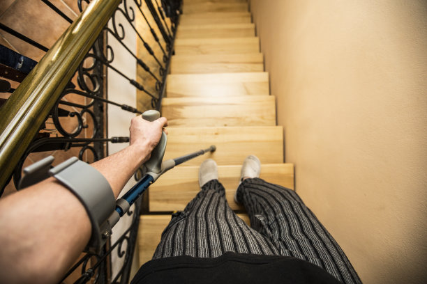 一名拄着拐杖走下楼梯的年轻人图片下载