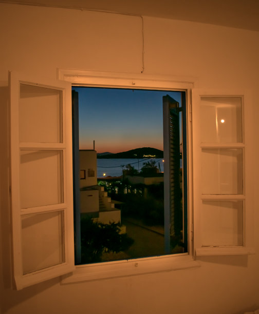 一个美丽的日落是通过一个开放的窗户在一个旅游的海边地方。图片下载