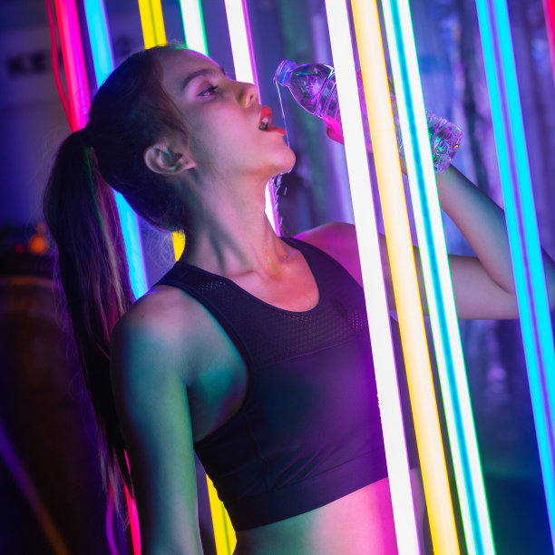 穿着运动内衣的20多岁亚洲女人在现代霓虹泰拳健身房训练，汗水飞溅图片下载