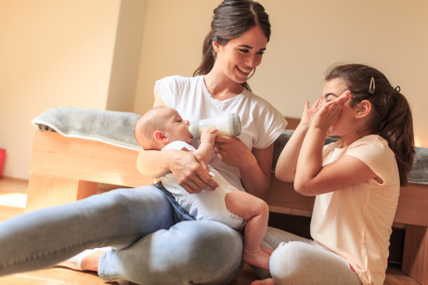 母亲和女儿一起坐在卧室里喂她的孩子。图片下载