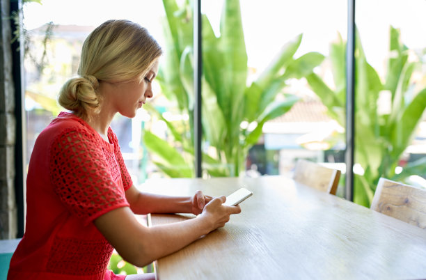 年轻的金发白种人自然千禧女工作手机在一个现代热带和明亮的办公室植物生活照片图片下载