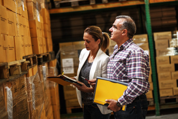 女经理和仓库工人检查仓库货架上的清单和存货。图片下载