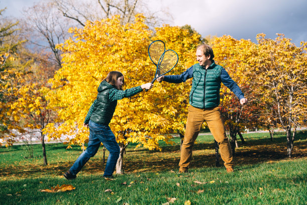 一对学龄的父子拿着羽毛球拍，笑眯眯地望着天空图片下载