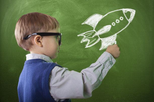 小男孩在绿色的黑板上画画图片下载