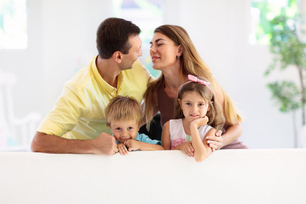 幸福的家庭。父母和孩子坐在沙发上。图片下载