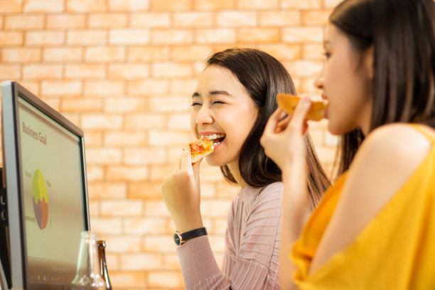 公司的亚洲女员工喜欢在工作时吃披萨图片下载