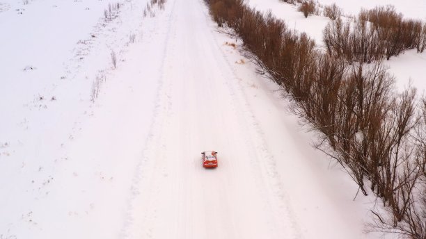 橙色汽车在雪地上行驶，俯视图。图片下载