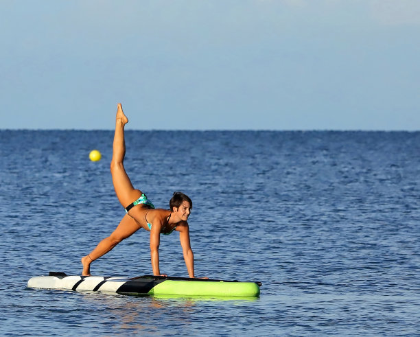 美丽的女人在划水板上保持平衡。图片下载