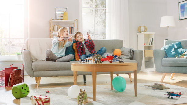 在家里:可爱的女孩在玩电子游戏，使用操纵杆控制器，她的弟弟为她欢呼。快乐的孩子玩电子游戏。图片下载