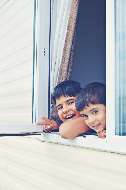 两个男孩的垂直照片，透过一扇开着的窗户和快乐的面部表情窥视图片下载