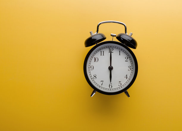 闹钟在黄色背景上俯视图。时间的概念。图片下载