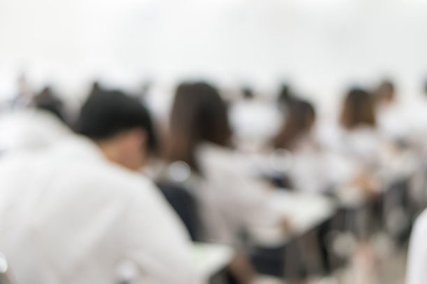 模糊学校背景的大学生在教室里写答案做考试图片下载