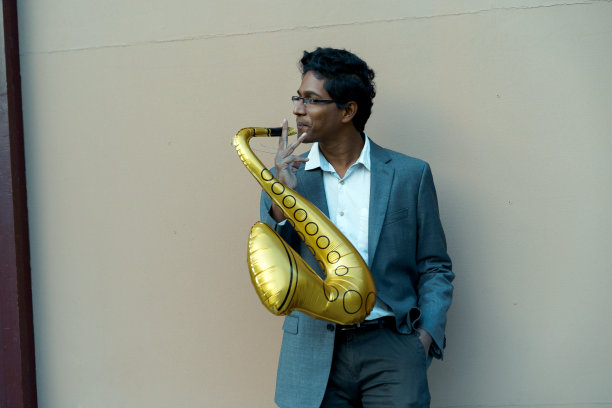 有趣英俊的印度男人，白色衬衫和商务套装，金色充气管图片下载