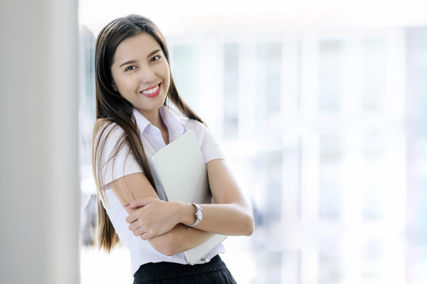 年轻的学生微笑着站在教室里拿着平板电脑的肖像。图片下载