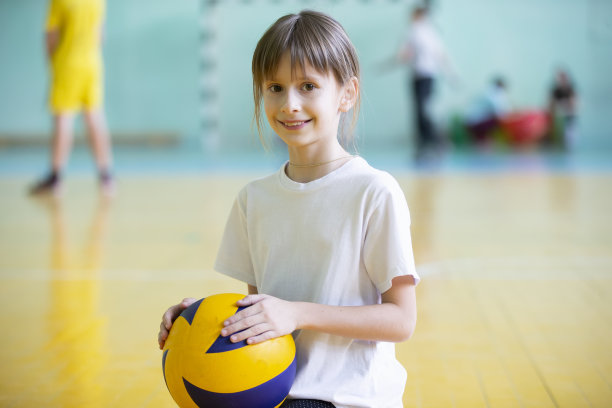 体育馆里的孩子。体育课上拿着球的女学生。穿运动服的女孩。孩子们的训练。运动的一天。图片下载