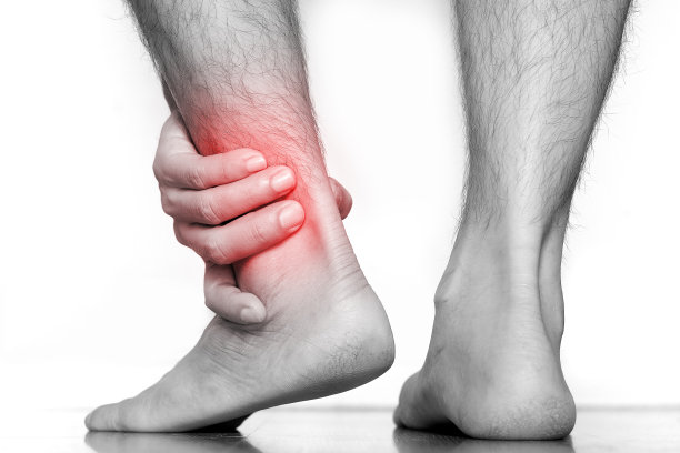 男人的腿和手，他抓住了他的脚踝，感到疼痛的照片图片下载